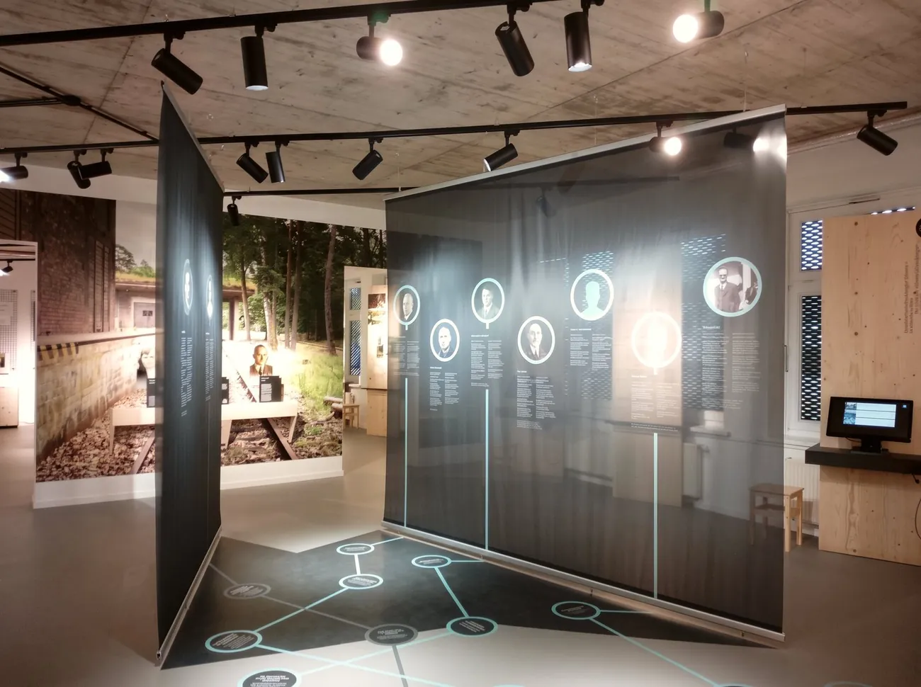 Ausstellungsraum der Gedenk- und Bildungsstätte Liebenau mit großen, halbtransparenten Porträtbahnen