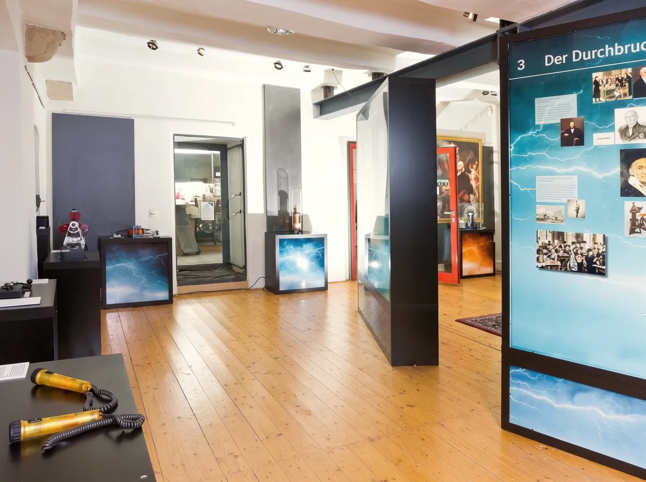 Die fertige Ausstellung „Achtung Hochspannung!“ mit beleuchteten Tafeln und Experimentiertischen